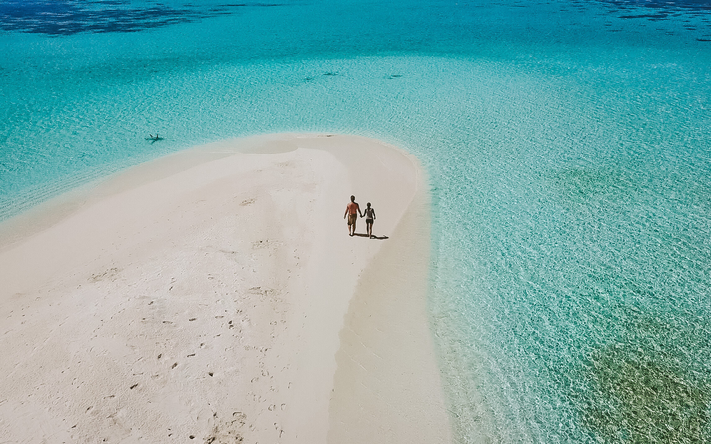 A couple walking together to the tip of Dhigurah