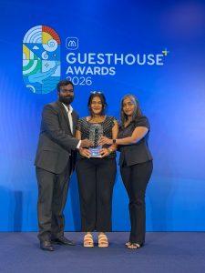 Three members of the Bliss Dhigurah team holding the Culinary Experience Award trophy on stage at the Guesthouse Awards 2026
